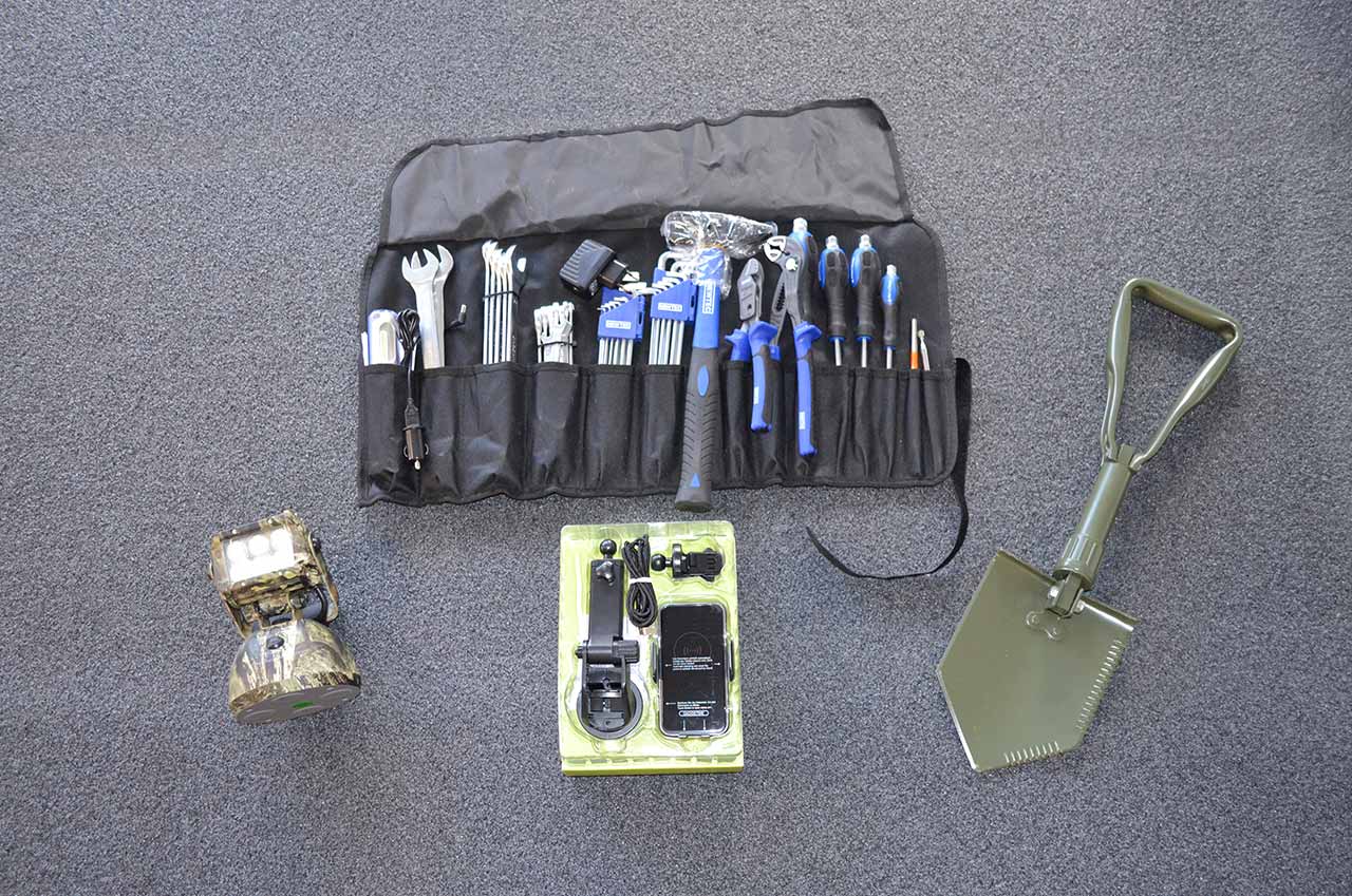 Werkzeugset mit Hammer, Schraubenschlüsseln, Schraubenziehern und Zangen in einer schwarzen Rolltasche, Klappspaten, Handyhalter und LED-Akku-Scheinwerfer