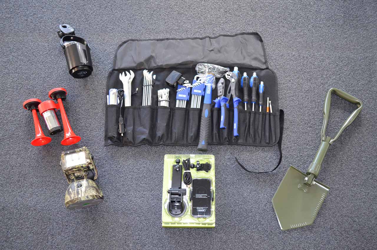 Werkzeugset mit Hammer, Schraubenschlüsseln, Schraubenziehern und Zangen in einer schwarzen Rolltasche, Klappspaten, Handyhalter, LED-Akku-Scheinwerfer, Drucklufthupe und Getränkehalter