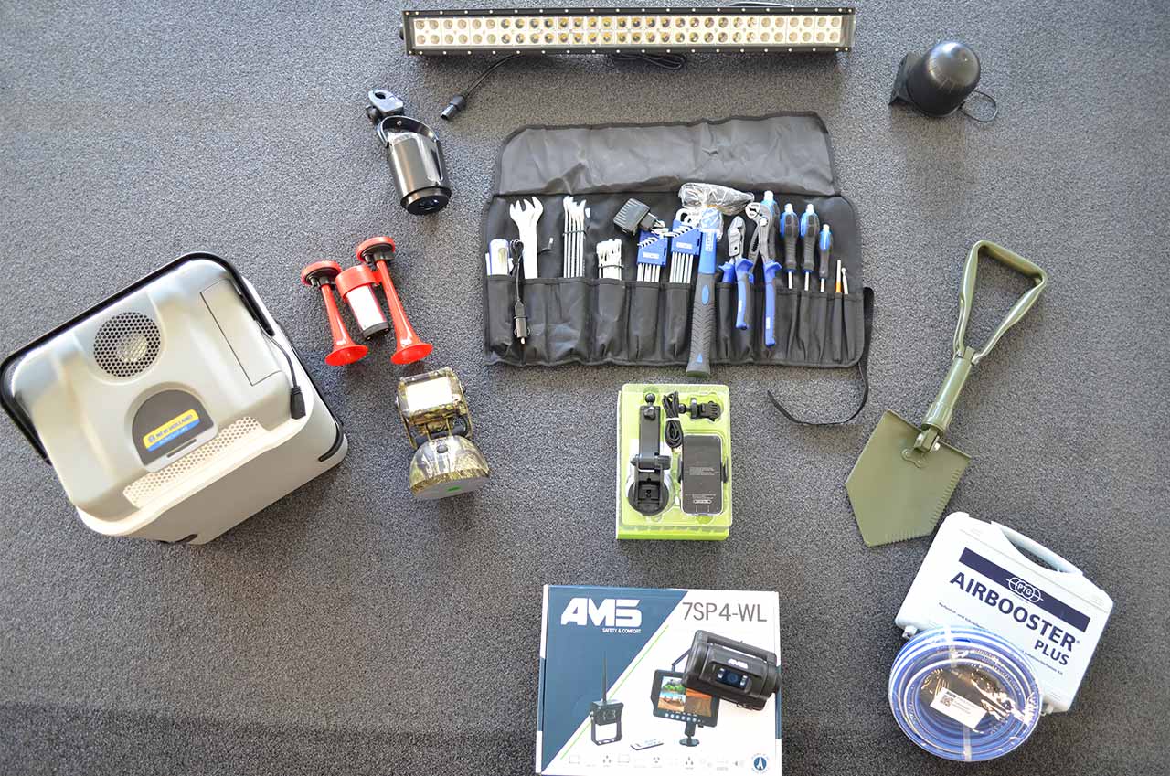Werkzeugset mit Hammer, Schraubenschlüsseln, Schraubenziehern und Zangen in einer schwarzen Rolltasche, Klappspaten, Handyhalter, LED-Akku-Scheinwerfer, Drucklufthupe, Getränkehalter, LED-Lichtleiste, Rückfahrkamera, Fixbox, Kamera mit Magnetfuß, Kühlbox und Reifenfüll-/Schnellentlüftungs-Set